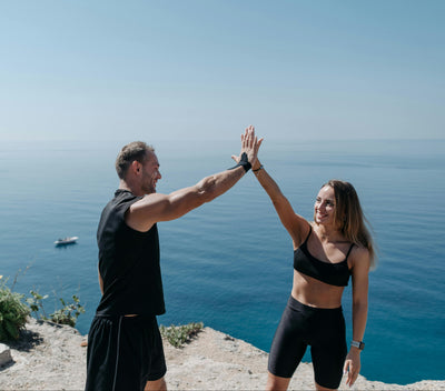 Two people giving each other a high-five with a scenic ocean view in the background